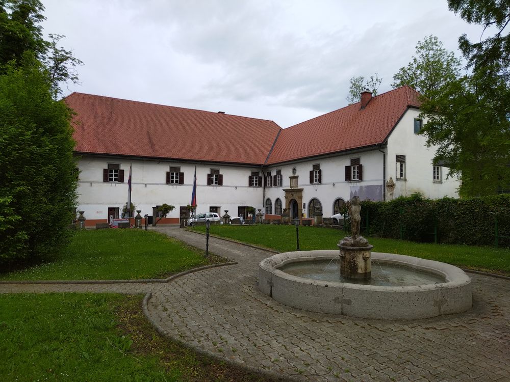 Zunanji pogled na dvorec Radlje po obnovi 2025, v ospredju vodnjak in manjši travnati park