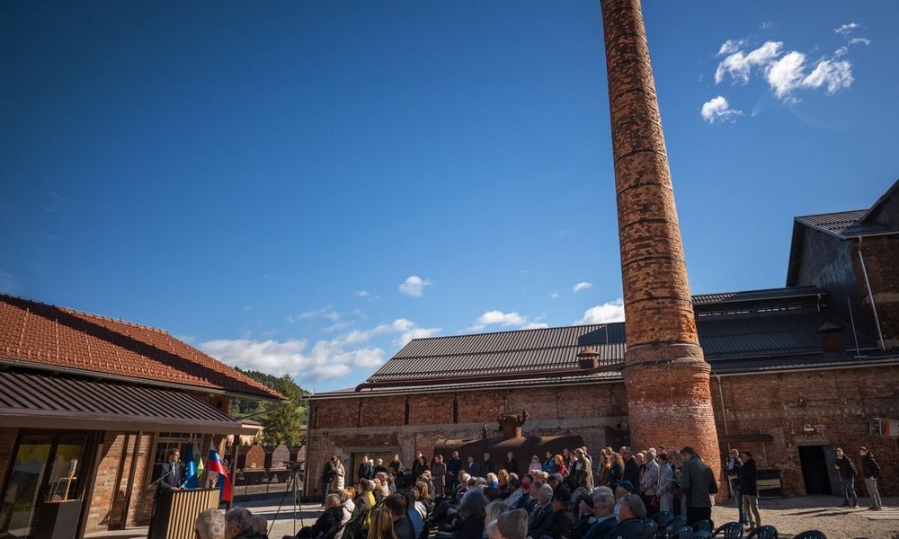 Ljudje sedijo ob stolpu stare železarne med slavnostnim govorom med otvoritvijo
