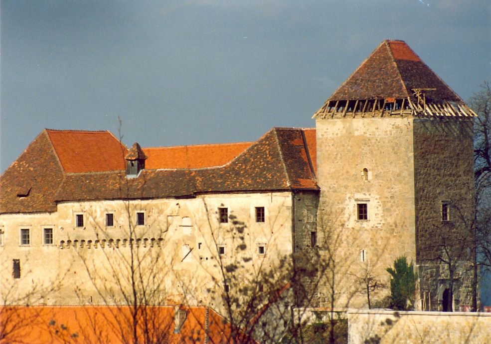 Pogled na grad Podsreda pred prenovo, večina strehe je &scaron;e stare rjave barve, medtem ko je nekaj delov že rdečih, na stolpu spodnji del strehe predstavljajo lesene deske, 