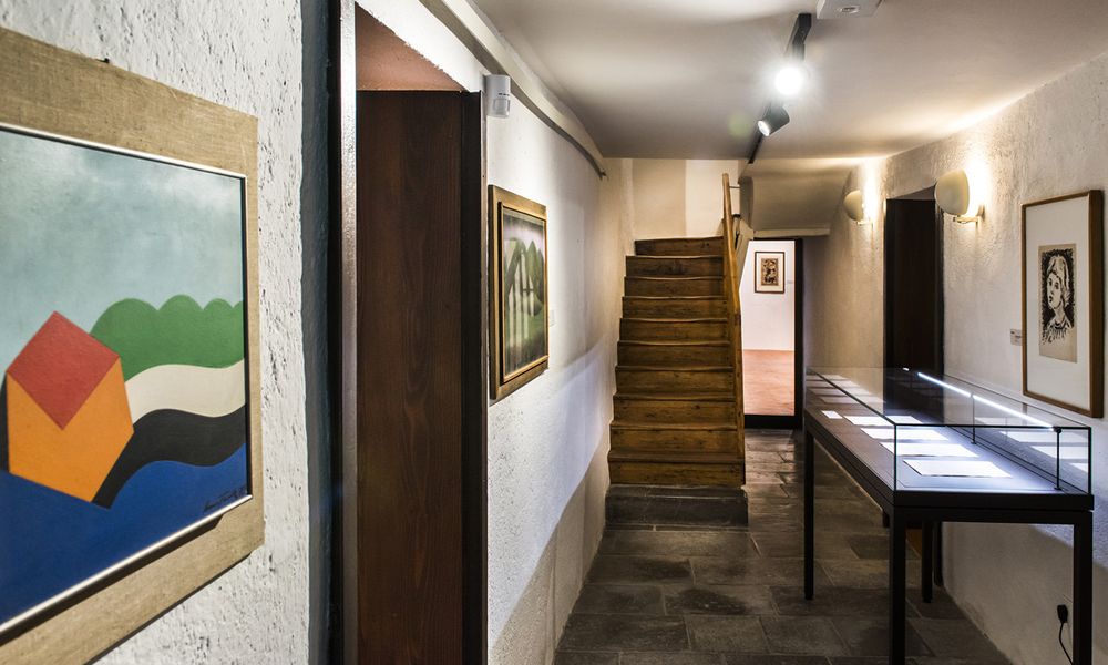 Ožji prostor v galeriji z umetniškimi deli, vitrino z listinami in lesenimi stopnicami