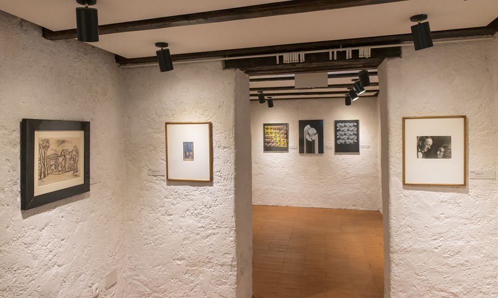 Razstava umetniških del v prenovljeni galeriji z belimi stenami in ploščicami na tleh